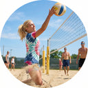 Woman playing beach volleyball with a clear blue sky and other players in the background.