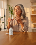 Woman taking a supplement with a glass of water in a home setting