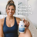 Woman holding a supplement bottle with text 'Create A Sense Of Wellbeing' in a home setting.