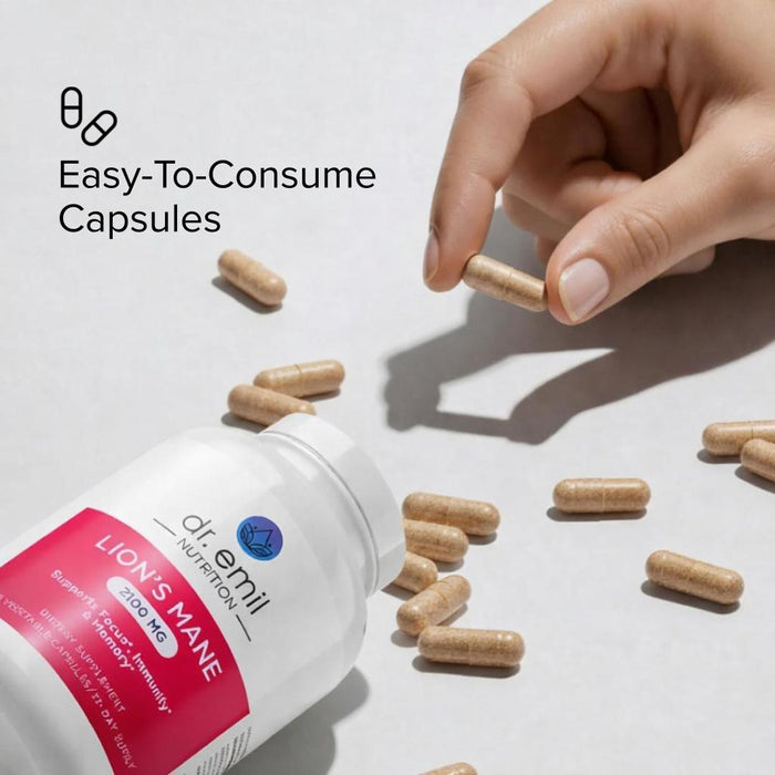 Hand picking up a supplement capsule from a bottle labeled 'Lion's Mane' on a light background.