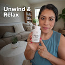 Woman holding a supplement bottle labeled 'SHTP PLUS' in a living room setting with text 'Unwind & Relax'.