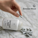 Hand pouring SHTP Plus supplement capsules onto a marble surface with 'Boosted Mood' text.