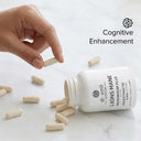 Hand picking a supplement capsule from an open bottle labeled 'Lions Mane Plus' with 'Cognitive Enhancement' text.