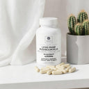 Bottle of Lion's Mane Mushroom Plus supplement with capsules on a white surface next to a cactus.