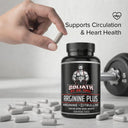 Bottle of Goliath by Dr. Emil Arginine Plus with a hand holding a supplement capsule and dumbbells in the background.