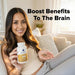Woman holding a bottle and some pills with text 'Boost Benefits To The Brain' in a home setting.