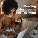Woman sitting on a couch with a laptop and coffee, with text 'Morning Mushrooms For The Mind' above her.