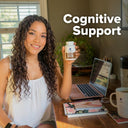 Woman holding a bottle labeled 'Cognitive Support' in a home office setting.