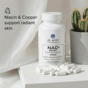 Dr. Emil NAD+ Boost supplement bottle with capsules on a light surface, featuring text about niacin and copper benefits.