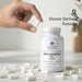 Bottle of Dr. Emil Nutrition Resveratrol Plus with a hand holding a capsule on a light background.
