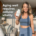 Woman holding a supplement bottle with text about cellular vitality in a living room setting
