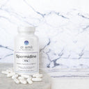 Bottle of Dr. Emil Nutrition Spermidine supplement with pills on a marble surface