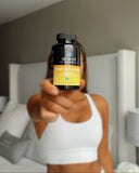 Person holding a bottle of Dr. Emil Total Gut Complex supplement in a blurred indoor setting